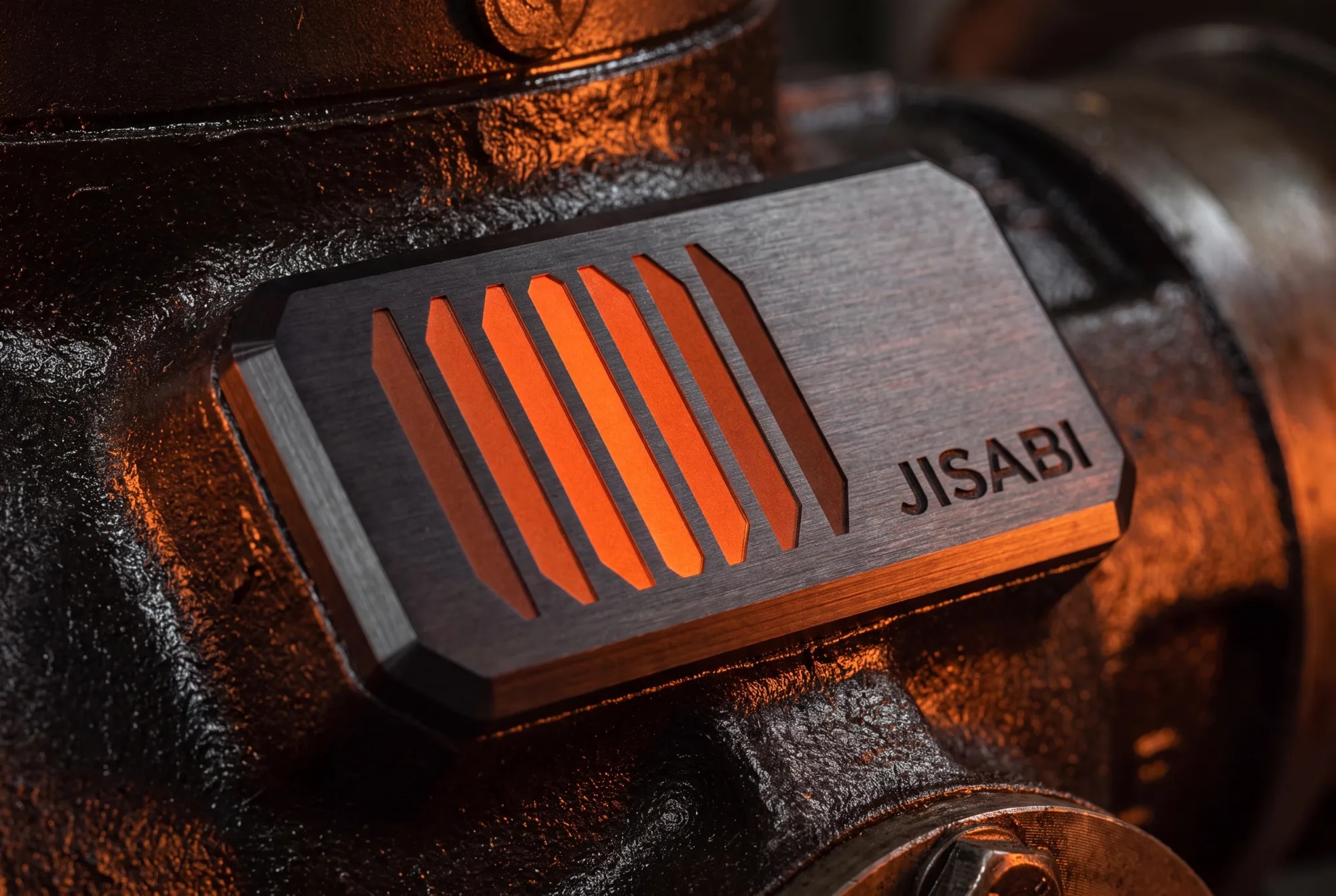The mark machined into an equipment badge, ember glowing through carbon.
