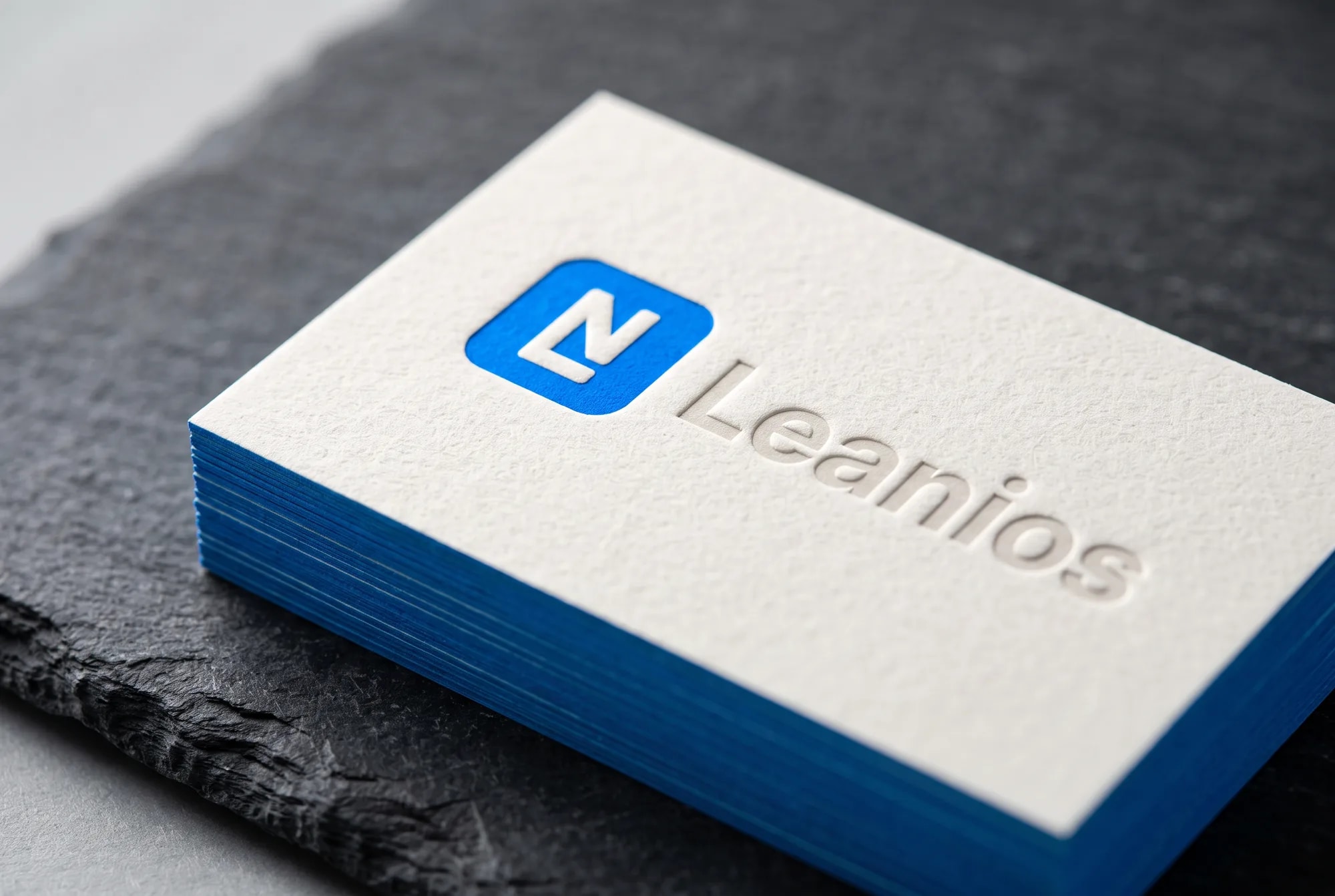 The identity in print: letterpress cards, the brand blue on the edges.
